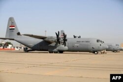 Petugas Irak berdiri di dekat pesawat Lockheed C-130 Hercules di Pangkalan Udara Muhammad Alaa, daerah kantong militer Bandara Internasional Baghdad, 24 April 2024, pada peringatan 93 tahun berdirinya angkatan udara Irak pada tahun 1931. (AHMAD AL-RUBAYE/AFP)