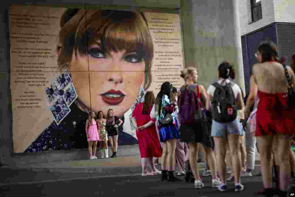 Taylor Swift fans pose for a photograph besides a mural, commissioned by London Mayor Sadiq Khan, before the first London concert of the Eras Tour.