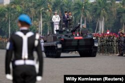 Presiden Joko Widodo didampingi Panglima TNI Yudo Margono berdiri di atas tank saat meninjau pasukan saat upacara HUT TNI ke-78 di kompleks Monumen Nasional (Monas) Jakarta, 5 Oktober 2023. (Foto: REUTERS/Willy Kurniawan )