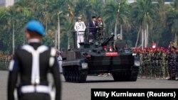 Presiden Joko Widodo didampingi Panglima TNI Yudo Margono berdiri di atas tank saat meninjau pasukan saat upacara HUT TNI ke-78 di kompleks Monumen Nasional (Monas) Jakarta, 5 Oktober 2023. (Foto: REUTERS/Willy Kurniawan )