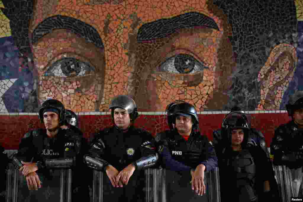 La policía antidisturbios observa frente a un mural que representa al héroe de la independencia Simón Bolívar mientras los partidarios del presidente de Venezuela, Nicolás Maduro, marchan para defender los resultados de las elecciones en Caracas, el 29 de julio de 2024.