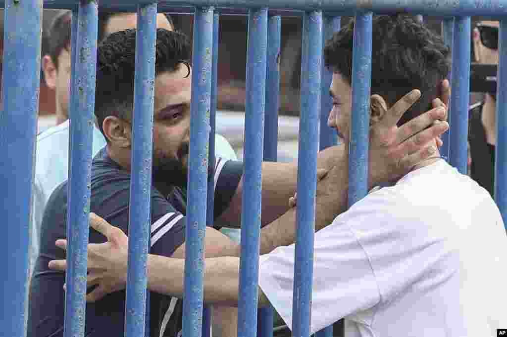 Syrian survivor Fedi, 18, right, one of 104 people who were rescued from the Aegean Sea after their fishing boat crammed with migrants sank, reacts as he reunites with his brother Mohammad, who came from Italy to meet him, at the port of Kalamata, Greece.