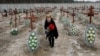 A local woman places flowers on graves of unidentified people killed by Russian soldiers during the occupation of Bucha town, outside Kyiv, Ukraine, February 24, 2023. REUTERS/Valentyn Ogirenko
