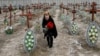 Một phụ nữ địa phương đặt hoa lên nấm mộ của những người vô danh bị lính Nga sát hại ở Ukraine.