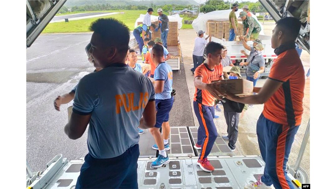 Polisi dan personel penjaga pantai menurunkan pasokan bantuan dari pesawat angkut C-130 angkatan udara di bandara Basco, provinsi Batanes , utara Manila, sebelum Super Topan Mawar melewati provinsi tersebut, 27 Mei 2023. (Foto: Handout/ Grup Operasi Taktis-Angkatan Udara Filipina (TOG 2- PAF) / AFP)