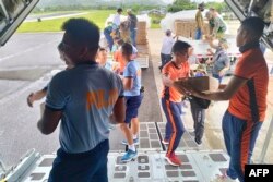 Polisi dan personel penjaga pantai menurunkan pasokan bantuan dari pesawat angkut C-130 angkatan udara di bandara Basco, provinsi Batanes , utara Manila, sebelum Super Topan Mawar melewati provinsi tersebut, 27 Mei 2023. (Foto: Handout/ Grup Operasi Taktis-Angkatan Udara Filipina (TOG 2- PAF) / AFP)