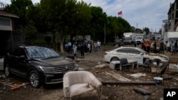 People walk next to scattered vehicles and furniture on the aftermath of floods caused by heavy rains in Istanbul, Turkey, Sept. 6, 2023. 