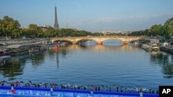 FILE - Athletes dive into the Seine River from the Alexander III bridge on the start of the first leg of the women's triathlon test event for the 2024 Paris Olympics in Paris, Aug. 17, 2023. 