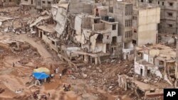 FILE - Rescuers and relatives of victims set up tents in front of collapsed buildings in Derna, Libya, Sept. 18, 2023. 