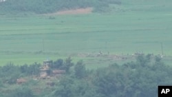 North Koreans work on a field near a North Korean military guard post, seen from the Unification Observation Post in Paju, South Korea, near the border with North Korea, July 21, 2024. 