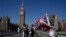 FILE - A woman holds a balloon featuring a Union Jack flag near the Houses of Parliament during a sunny day in London, Sept. 4, 2023. 