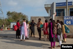 FILE - Job aspirants talk with a hiring agent outside the Foxconn factory, where workers assemble iPhones for Apple in Sriperumbudur near Chennai, India, April 1, 2024.