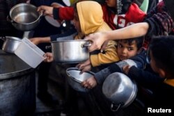 Palestinian children wait to receive food cooked by a charity kitchen amid shortages of food supplies in Rafah, in the southern Gaza Strip, March 5, 2024.