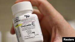 FILE - A pharmacist holds a bottle OxyContin made by Purdue Pharma at a pharmacy in Provo, Utah, May 9, 2019. On Tuesday, Purdue Pharma received U.S. court approval for a 60-day freeze on lawsuits against its owners, the Sackler family.