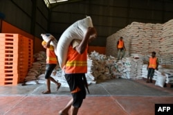 Pekerja membawa karung beras impor dari Thailand di gudang Bulog di Lambaro, Aceh, 16 Mei 2023. (Foto: Chaideer Mahyuddin/AFP)