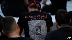 Para pendukung kelompok Hizbullah yang didukung Iran, mengenakan kaus yang dihiasi foto para kombatan yang tewas dalam pertempuran melawan Israel, di tengah perayaan Ashura di Beirut, Lebanon, Kamis, 17 Juli 2024. (Foto: Bilal Hussein/AP Photo)