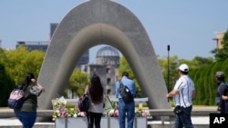 Visitors pray before flowers placed at the Hiroshima Peace Memorial Park, ahead of the Group of Seven nations' meetings in Hiroshima, western Japan, May 17, 2023.