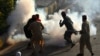 Pakistan Tehreek-e-Insaf (PTI) party activists and supporters of former Pakistan's Prime Minister Imran clash with police amid teargas during a protest against the arrest of their leader, in Peshawar on May 9, 2023.