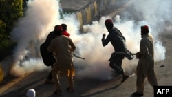 Pakistan Tehreek-e-Insaf (PTI) party activists and supporters of former Pakistan's Prime Minister Imran clash with police amid teargas during a protest against the arrest of their leader, in Peshawar on May 9, 2023.