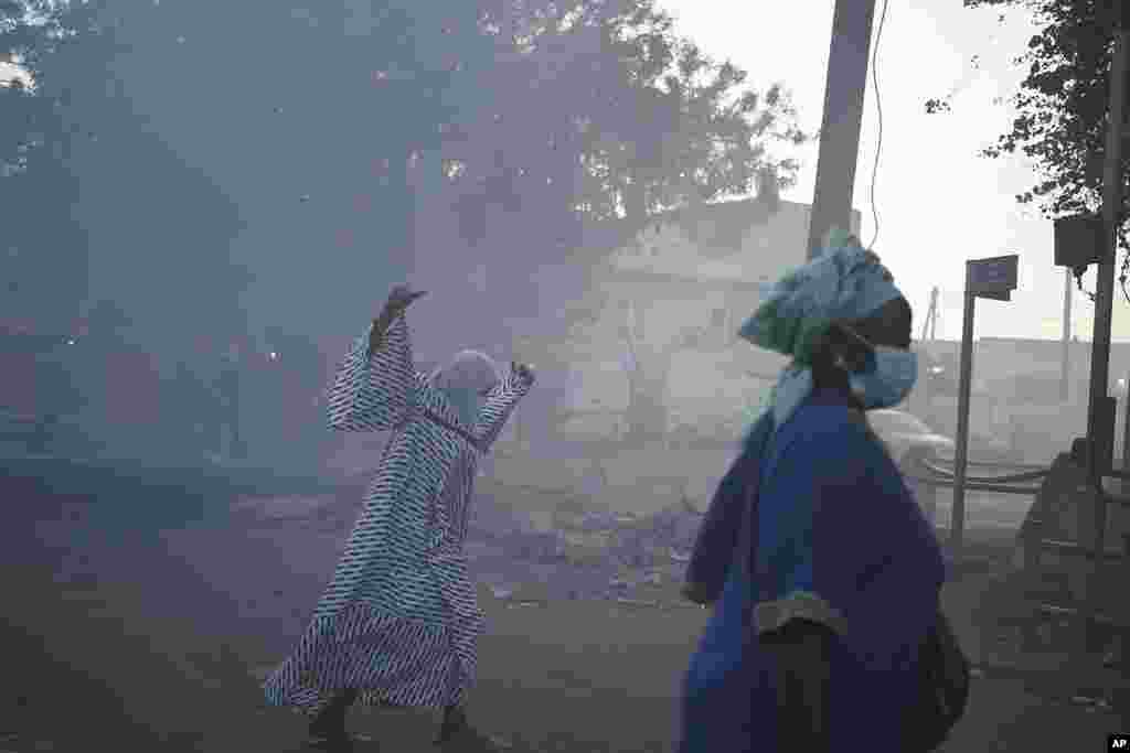 Women cross a street filled with smoke during clashes between demonstrators and police in Dakar, Senegal, Saturday, June 3, 2023.&nbsp;