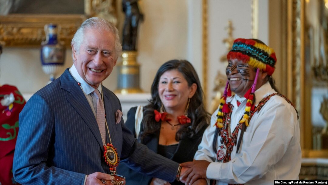 Raja Inggris Charles III menerima cendera mata dari pemimpin adat Amazon, Domingo Peas, dalam resepsi di Istana Buckingham, London, Jumat, 17 Februari 2023. (Foto: Kin Cheung/Pool via Reuters)