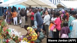 FILE: friends and relatives who bow to the photos and names of those who disappeared from a shipwreck in Libreville on March 5, 2023.