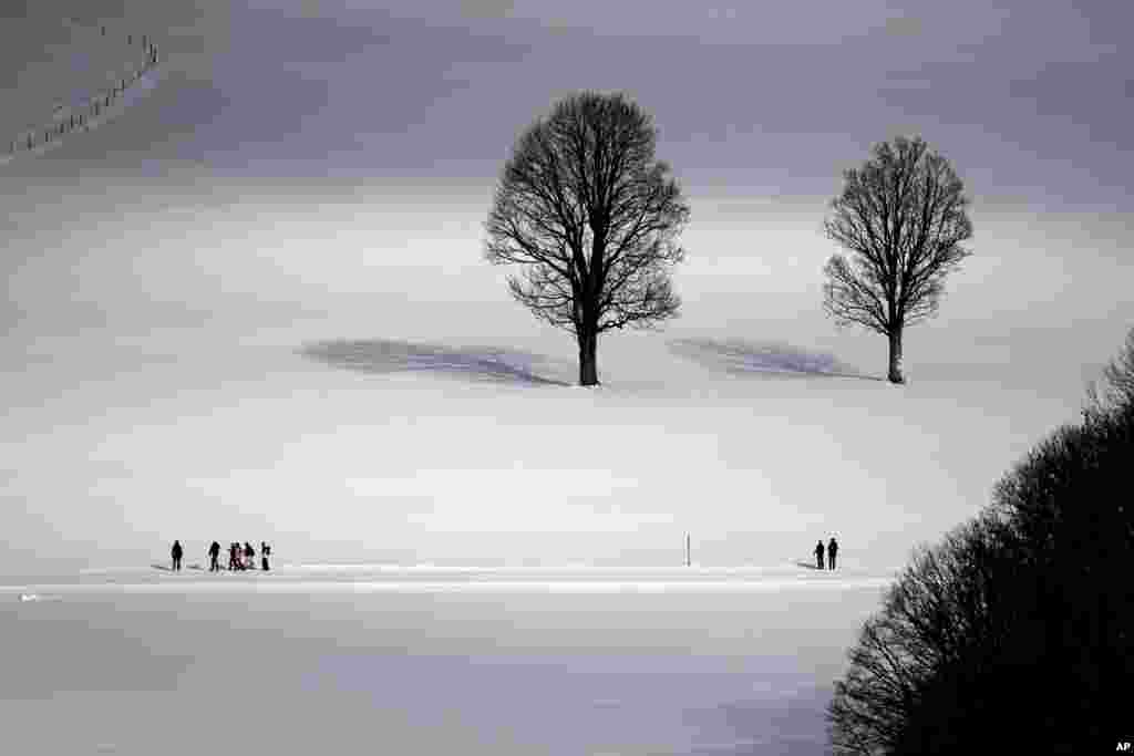 People walk through a snow covered landscape in Ramsau, Austria, Dec.16, 2023.