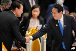 윤석열 한국 대통령과 기시다 후미오 일본 총리가 지난해 11월 캄보디아 프놈펜에서 열린 아세안-동아시아 정상회의장에서 악수하고 있다.