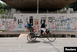 A rickshaw passes by a wall covered in graffiti in the University of Dhaka area, a day after the resignation of Bangladeshi Prime Minister Sheikh Hasina, in Dhaka, Bangladesh, Aug. 6, 2024.