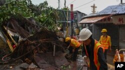 Workers clear debris near shophouses after Typhoon Saola struck the city with strong winds and rain, in Hong Kong, Sept. 2, 2023. 