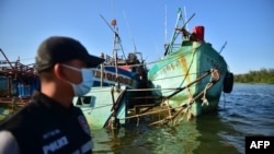 Một sĩ quan Cảnh sát biển Hoàng gia Thái Lan đứng trước hai tàu đánh cá Việt Nam bị bắt giữ đang neo đậu ven biển ở tỉnh Narathiwat hồi tháng 4/2020. Việt Nam đặt mục tiêu chấm dứt đánh bắt cá hải sản trái phép ở vùng biển nước ngoài vào tháng 5 năm nay.