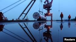 中国江苏省南京市一个港口的工人在使用起重机吊起中国建筑工业能源建设集团的海上风能设备。（2019年4月23日）