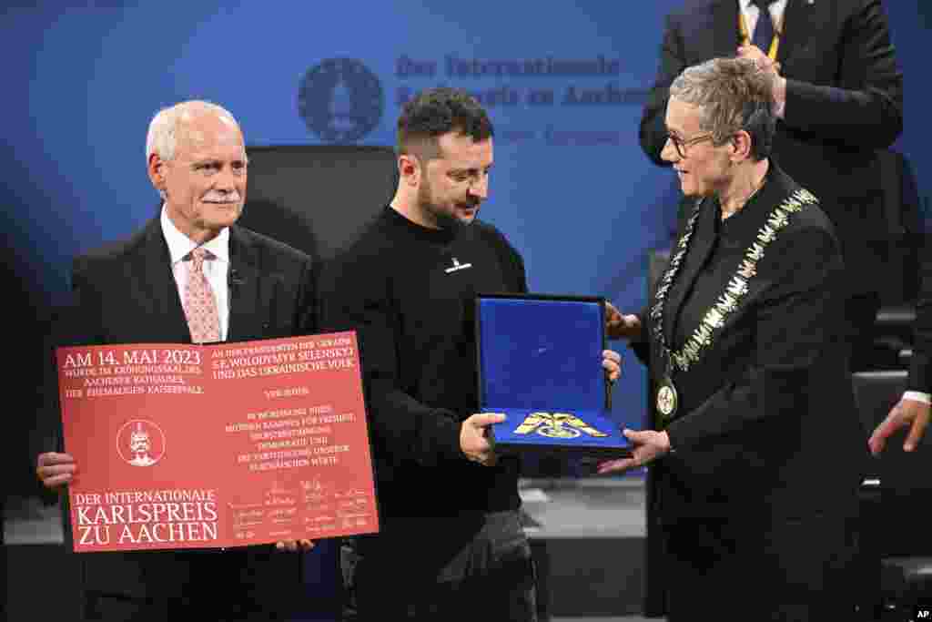 Ukrainian President Volodymyr Zelenskyy, center, receives the Charlemagne Prize for Services to European Unity from the Lord Mayor of Aachen Sibylle Keupen, right, in Aachen, Germany.