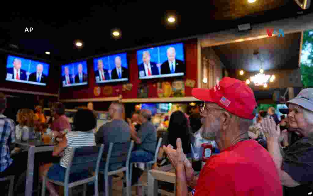  Don Hornberger (de rojo) y Beth Hornberger (con gorro gris), ambos de Fairfield, Ohio, escuchan atentamente al expresidente Donald Trump durante el debate presidencial de CNN. 