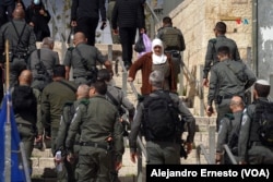 Una anciana palestina camina entre policías israelíes en la Puerta de Damasco de la Ciudad Vieja de Jerusalén.