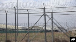 FILE - A hangar can be seen behind barbed wire fencing at Bagram Air Base after the U.S. military left the facility, in Parwan province, north of Kabul, Afghanistan, July 5, 2021.