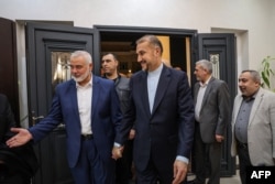 Pemimpin Hamas yang berbasis di Qatar Ismail Haniyeh (kiri) menyambut Menteri Luar Negeri Iran Hossein Amir Abdollahian (tengah), di Doha. (Foto: AFP)