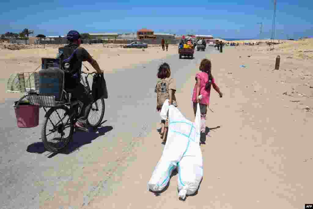 Palestinian children use a hazmat suit to transport belongings as they flee the area of Tel al-Sultan in Rafah in the southern Gaza Strip.