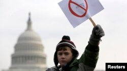 Peyton Tremont, tujuh tahun, melambaikan kertas di tengah aksi protes masyakarat menuntut pengendalian senjata di dekat Capitol AS, Washington, 26 Januari 2013. (Foto: REUTERS/Jonathan Ernst)