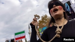 FILE - A member of the Iranian community living in Turkey holds a rope as writing on her neck reads, "No to the death penalty," during a rally in support of anti-government protesters in Iran, in Istanbul, Turkey, Nov. 19, 2022. 