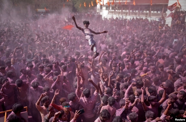 FILE - Hindu devotees daubed in colour throw a fellow devotee in the air as they celebrate Holi, the festival of colours, at a temple premises in Salangpur in the western state of Gujarat, India, March 7, 2023. (REUTERS/Amit Dave)