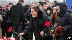 People lay flowers at the fence next to Crocus Town Hall on March 23, 2024 on the western edge of Moscow.