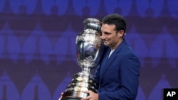 El entrenador de fútbol de Argentina, Lionel Scaloni, lleva el trofeo de la Copa América durante la ceremonia del sorteo del torneo de fútbol Copa América, el jueves 7 de diciembre de 2023, en Miami. (Foto AP/Lynne Sladky)