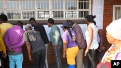 People look for their names, outside a polling station in Harare, Thursday, Aug. 24, 2023. Voting is still underway in Zimbabwe. 