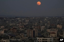 The supermoon rises in the sky over the houses of Gaza City, Wednesday, Aug. 30, 2023. (AP Photo/Adel Hana)