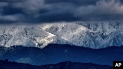 FILE - Storm clouds and snow are seen over the San Gabriel mountain range behind Griffith Observatory in the Hollywood Hills part of Los Angeles on Feb. 26, 2023.