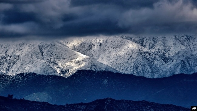 FILE - Storm clouds and snow are seen over the San Gabriel mountain range behind Griffith Observatory in the Hollywood Hills part of Los Angeles on Feb. 26, 2023.