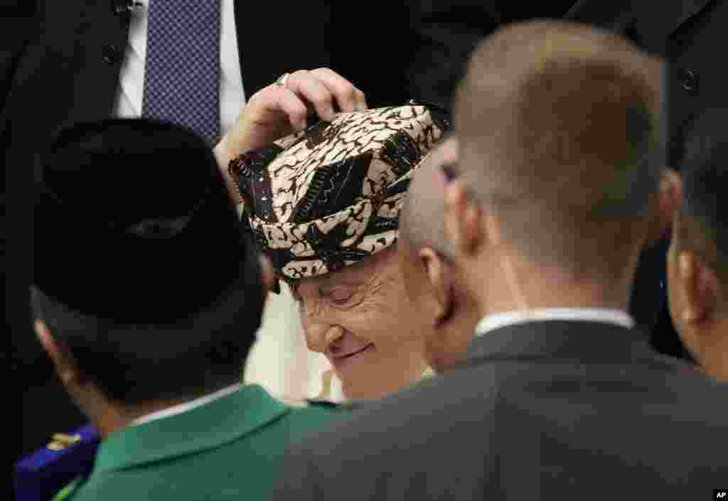 Pope Francis wears a traditional hat given by an Indonesian faithful on the occasion of the weekly general audience at the Vatican.