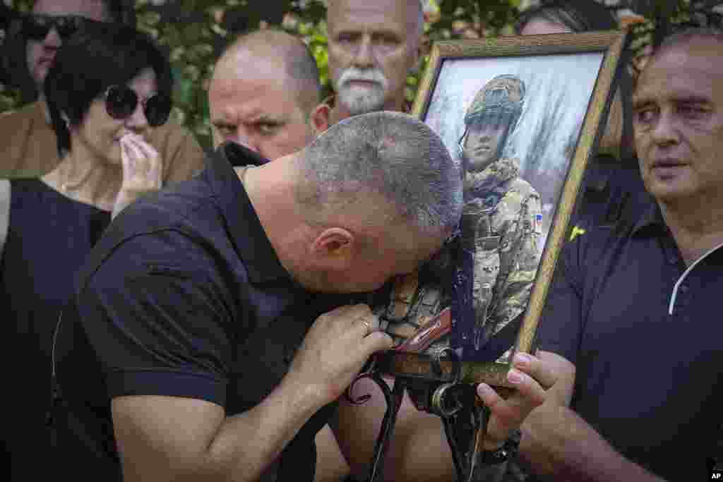 The father of Ihor Voyevodin cries as he holds a photo of his son, a student of Kyiv Shevchenko University and an Azov volunteer soldier, who was killed in a battle with Russian troops during a farewell ceremony at the University in Kyiv, Ukraine.