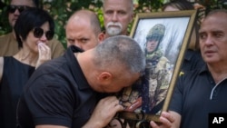 The father of Ihor Voyevodin cries as he holds a photo of his son, a student of Kyiv Shevchenko University and an Azov volunteer soldier, who was killed in a battle with Russian troops during a farewell ceremony at the University in Kyiv, Ukraine.